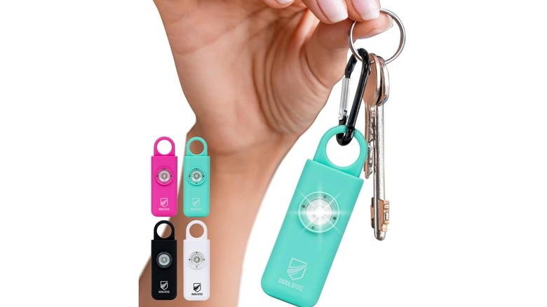 A woman holding a keychain featuring a mint-colored Original Defense personal safety alarm.