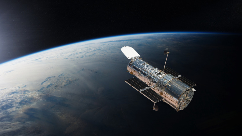 The Hubble Space Telescope floating in orbit above the Earth's surface.
