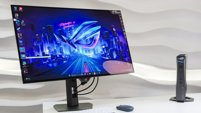 An OLED monitor on a clean desk with a minimalist dark wallpaper and no visible static UI elements.