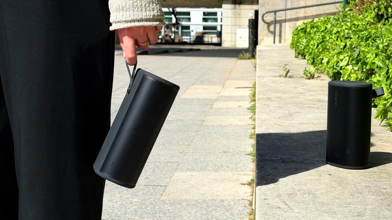 A girl holding a Sonos Play speaker to demonstrate its compact size and integrated loop.