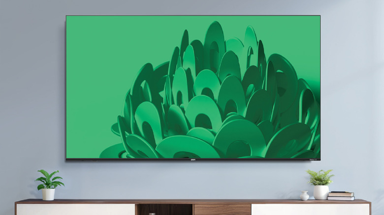 A massive 75-inch Onn 4K TV mounted on a wall in a minimalist room.