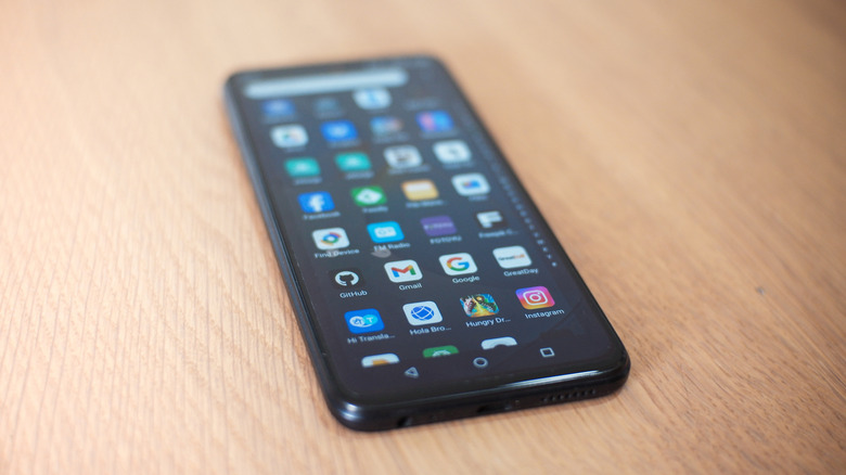 A smartphone lying on a surface showing various colorful app icons on its screen.
