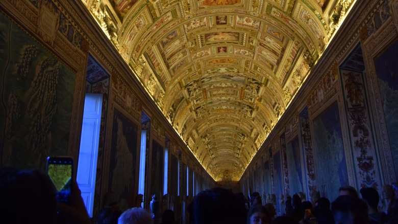 Ornate, high-ceilinged gallery within the Vatican Museums leading toward the chapel.