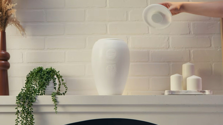 The Eternal Playlist Urn placed on a white mantel surrounded by memorial candles and flowers.