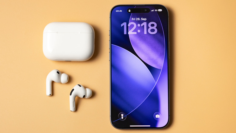 AirPods Pro 3 charging case and earbuds resting on a surface next to a modern iPhone.