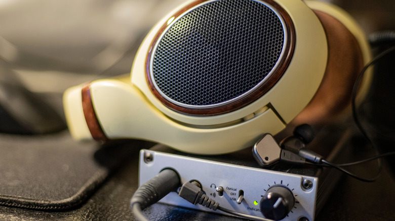 High-fidelity over-ear headphones resting on a professional external DAC and headphone amplifier unit.