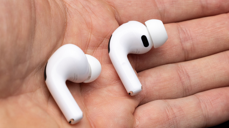 A person holding the AirPods Pro 3 earbuds between their fingers to show the internal sensor side.