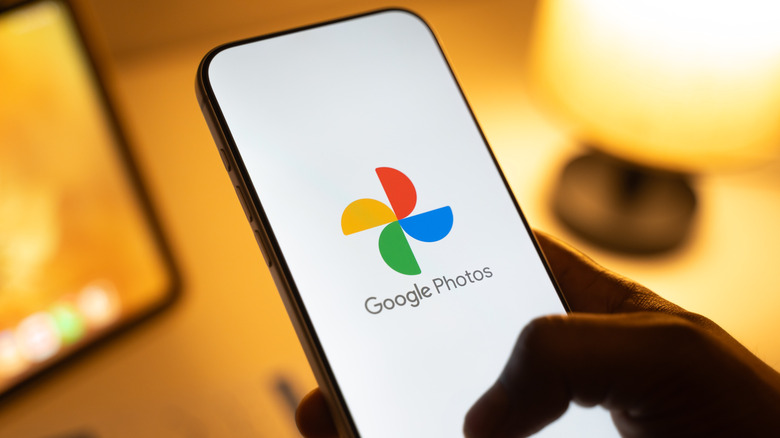 A person holding a phone showing the Google Photos logo.