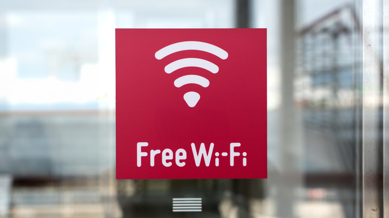 A bright red sign on a glass door advertising free public Wi-Fi access.