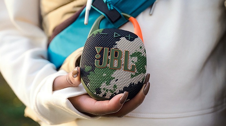 JBL Clip 5 attached to the backpack of a person.