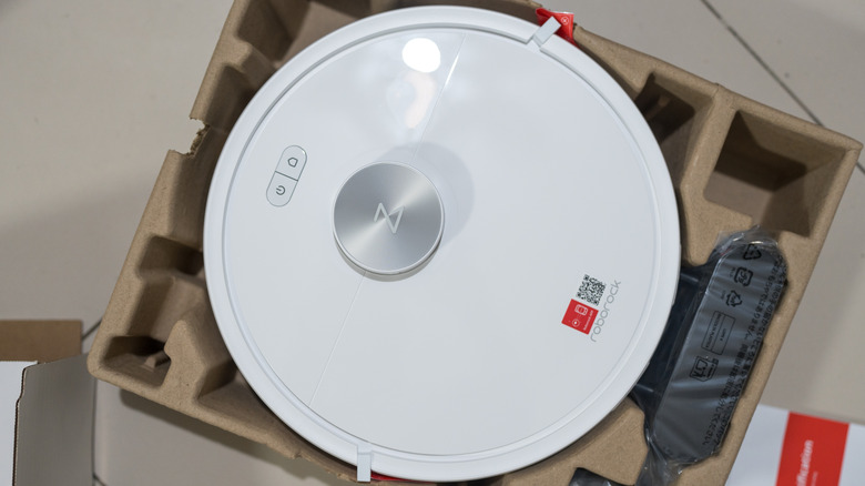 A new Roborock robot vacuum being carefully unboxed from its original packaging.