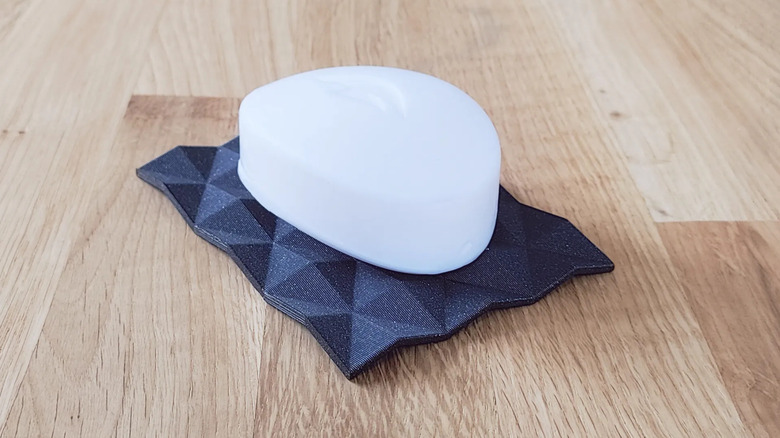 A bar of soap resting on a 3D printed soap dish with drainage holes.