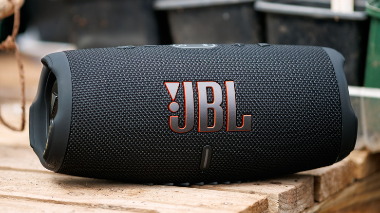 JBL Bluetooth speaker resting on a wooden table in an outdoor patio setting.