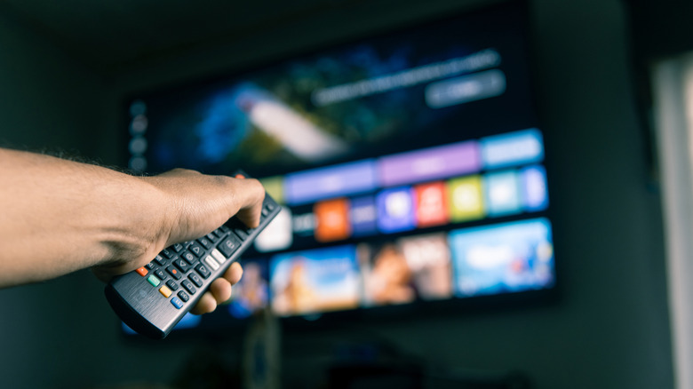 A person holding a remote control while browsing a streaming app on a smart TV.