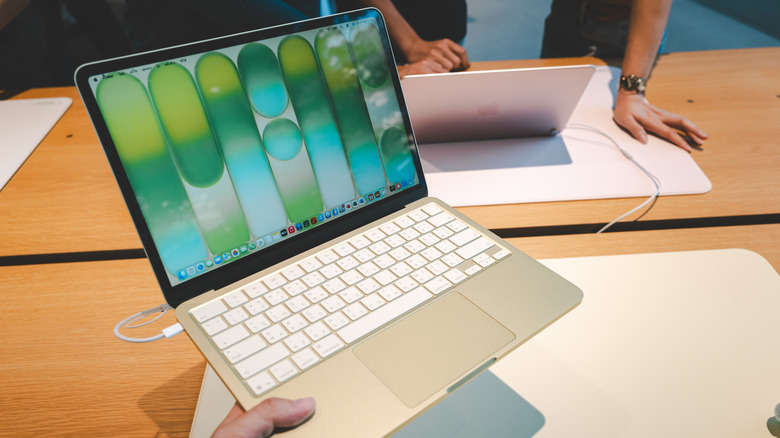 Close up of a person holding the thin MacBook Neo laptop.