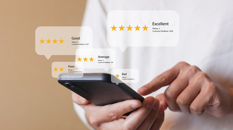 A person using a smartphone with digital icons for reviews and analysis floating above it.