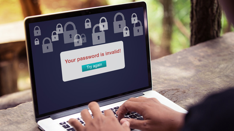 A person looking at a laptop screen displaying an 'invalid password' error message.