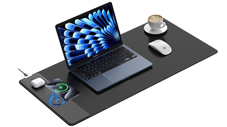 An XXL wireless charging mouse pad on a desk simultaneously charging a smartphone and earbuds.