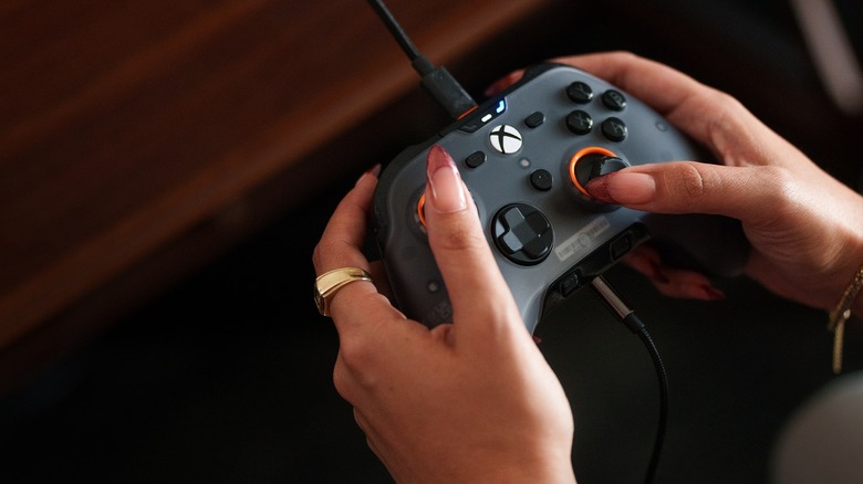 A woman holding a Scuf Valor Pro controller, demonstrating how her fingers align with the rear paddles.