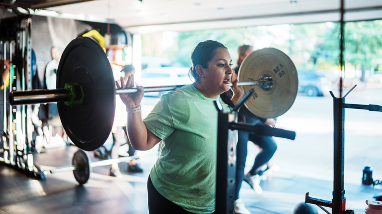A woman in athletic wear performing exercises in a garage converted into a home fitness studio.