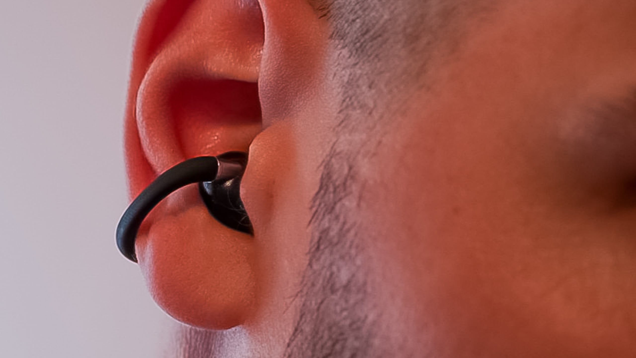 Close-up of a person wearing the white EarFun Clip 2 earbud clipped onto the outer ear.