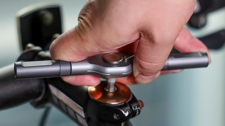 A ratcheting screwdriver being used to adjust a bolt on a bicycle's handlebar stem.
