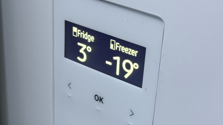 A digital thermometer showing temperatures in a fridge and freezer compartment.