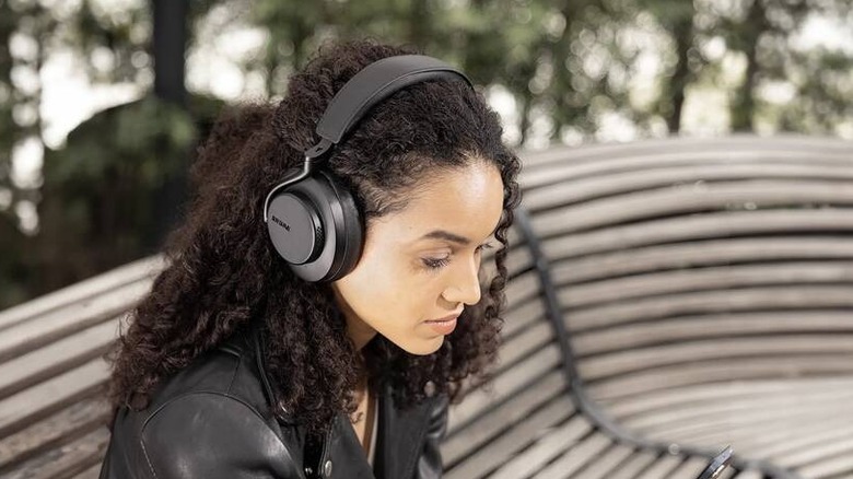 A person using Shure Aonic 50 Gen 2 headphones in an outdoor setting.