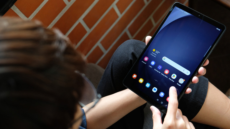 A user holding the sleek Samsung Galaxy Tab A9 Plus with one hand, highlighting its lightweight design.