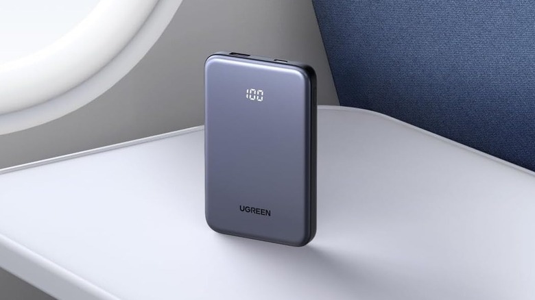 A gray Ugreen Nexode 10K power bank sitting on an airplane tray table.