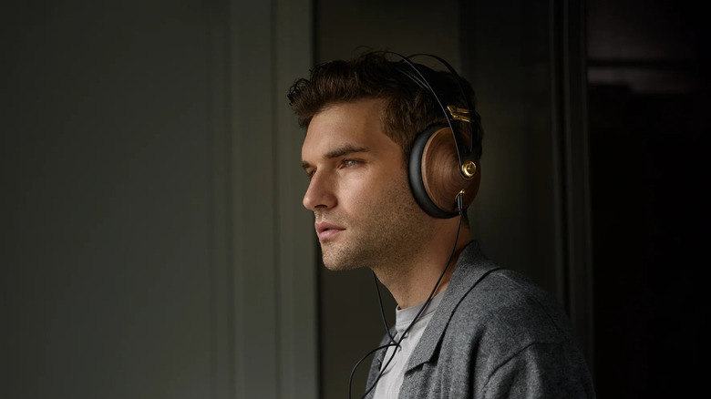 A person wearing Meze Audio 99 Classics headphones with walnut wood earcups.