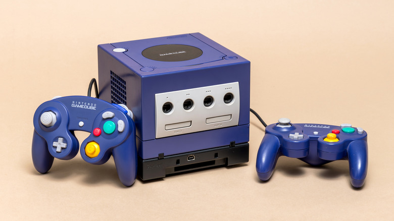 An indigo Nintendo GameCube console alongside its wired controller, signifying the legacy hardware supported by early Wii models.