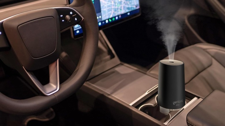 A compact GENIANI portable USB humidifier releasing mist inside a car's cabin.