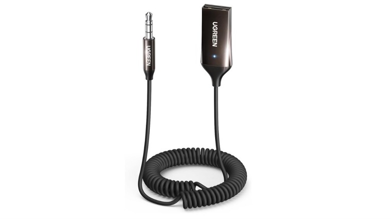 A UGREEN Bluetooth receiver with a coiled auxiliary cable plugged into a car's audio system.