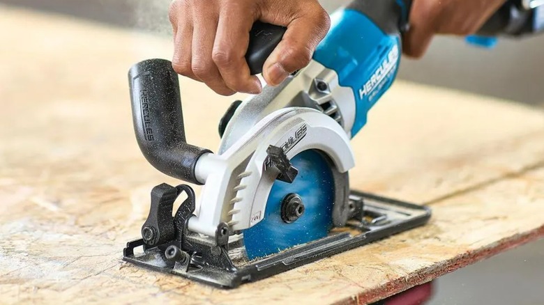 A Hercules 20V brushless compact circular saw cutting through a wooden board.