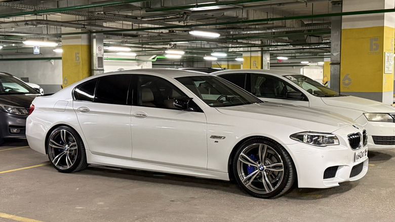 A white BMW F10 parked in a parking garage.