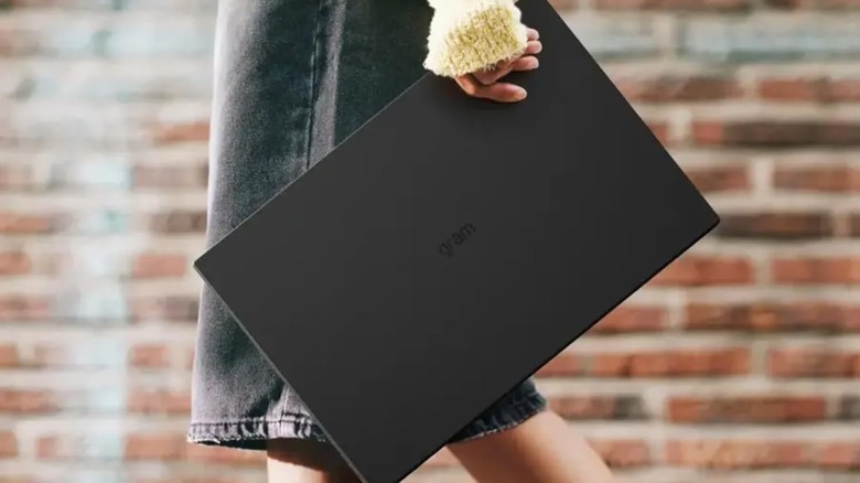A person holding the large but lightweight LG Gram 17-inch laptop with one hand.