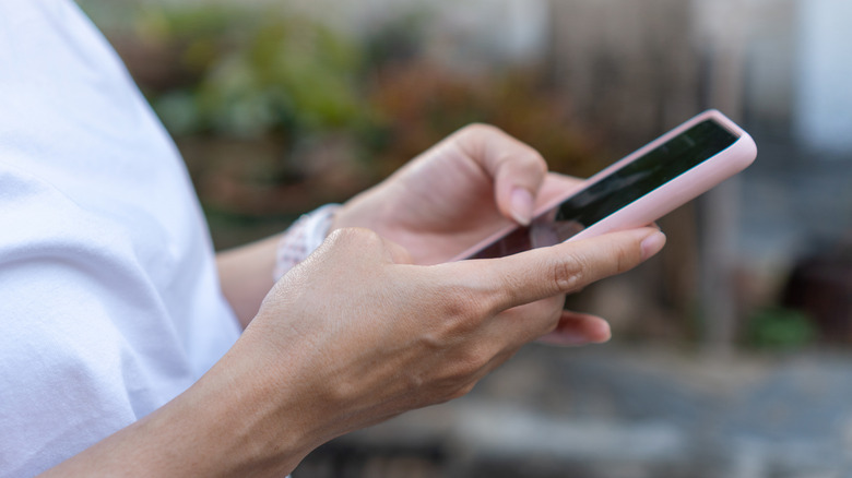 Close-up of a person's hands holding and interacting with a smartphone screen.