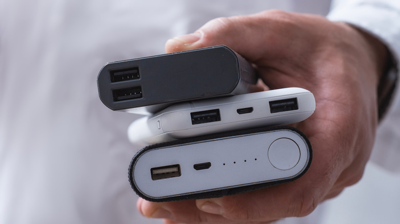 A person holding three different portable power banks in their hand.