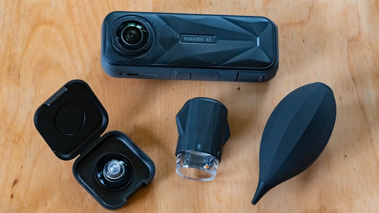 Close-up of the Insta360 X5 camera sitting next to its 11-piece lens replacement kit components.
