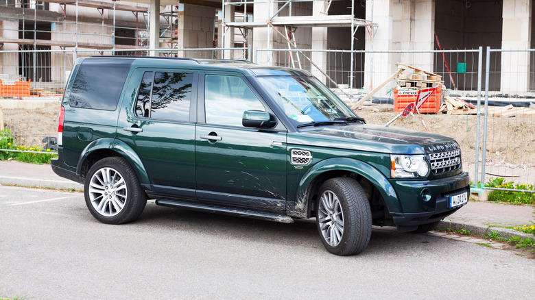 A green 2014 Land Rover Discovery parked near a construction site.
