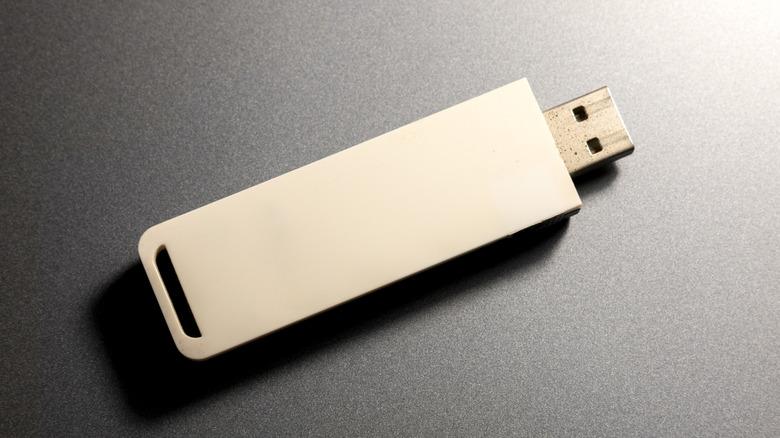 A standard USB flash drive sitting on a flat surface.