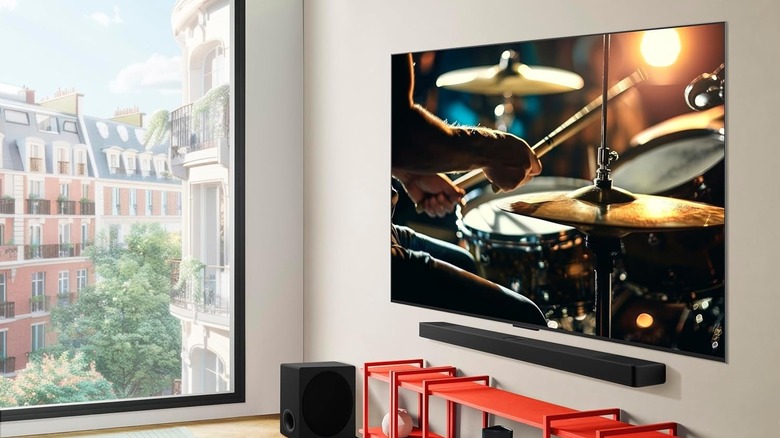 A sleek LG OLED TV mounted on a wall above a soundbar, displaying a high-contrast cinematic scene.
