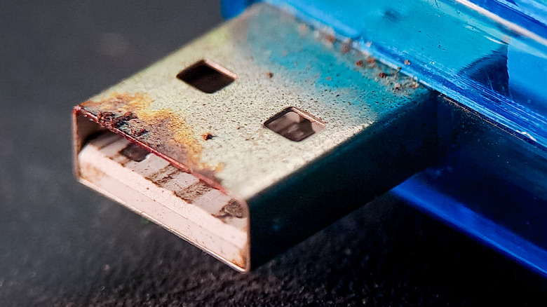 Extreme close-up of a corroded USB connector with green oxidation visible on the metal contacts.