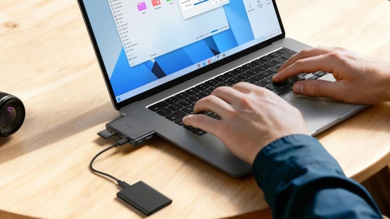 Close-up of a user utilizing the compact detachable 6-in-1 USB-C hub with a laptop in a mobile setting.