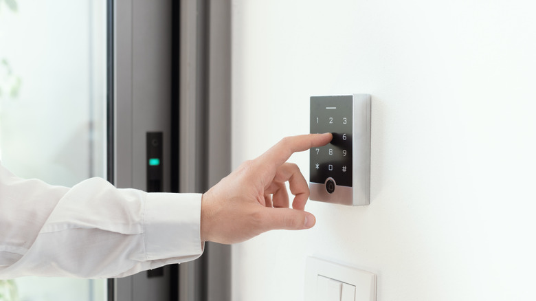 A person entering a code into a home security system keypad.