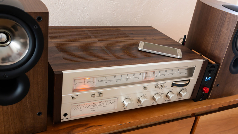 Close-up of a smartphone on a vintage audio amplifier illustrating the evolution of audio technology.