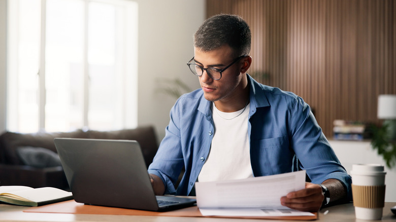 A professional man working on a laptop at a bright, modern office desk.