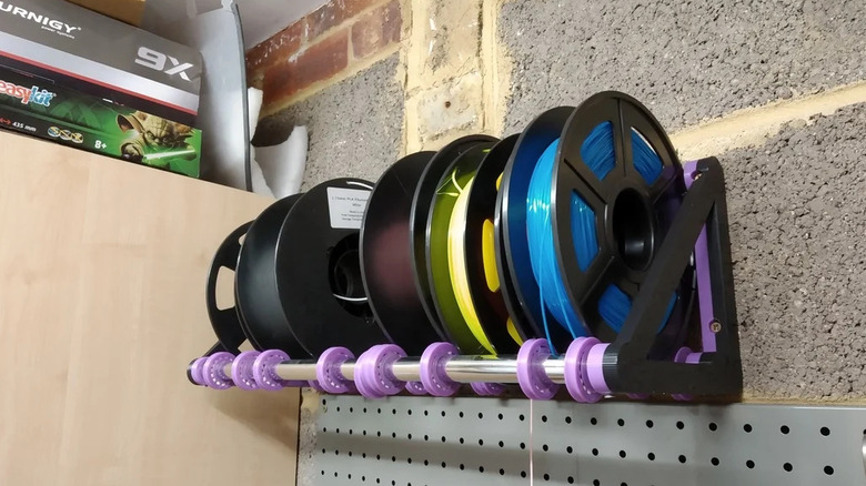 A custom-built rack holding multiple spools of colorful 3D printing filament.