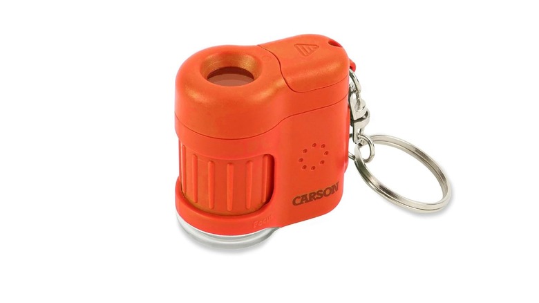 An orange Carson MicroMini 20x microscope with an adjustable scope and keychain attachment.